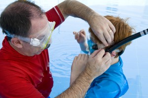 father helping child with snorkel gear